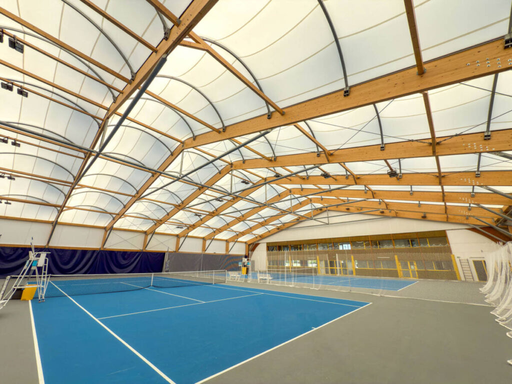 SMC2 a conçu et construit une halle sportive à Trélissac avec 4 courts de tennis et 2 de padel, alliant bois, acier et membrane textile.